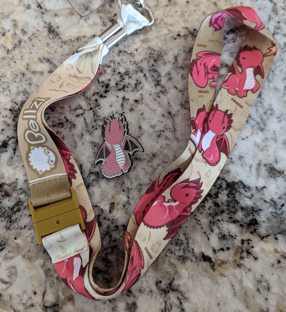 A lanyard with dragons on it with a matching pin.